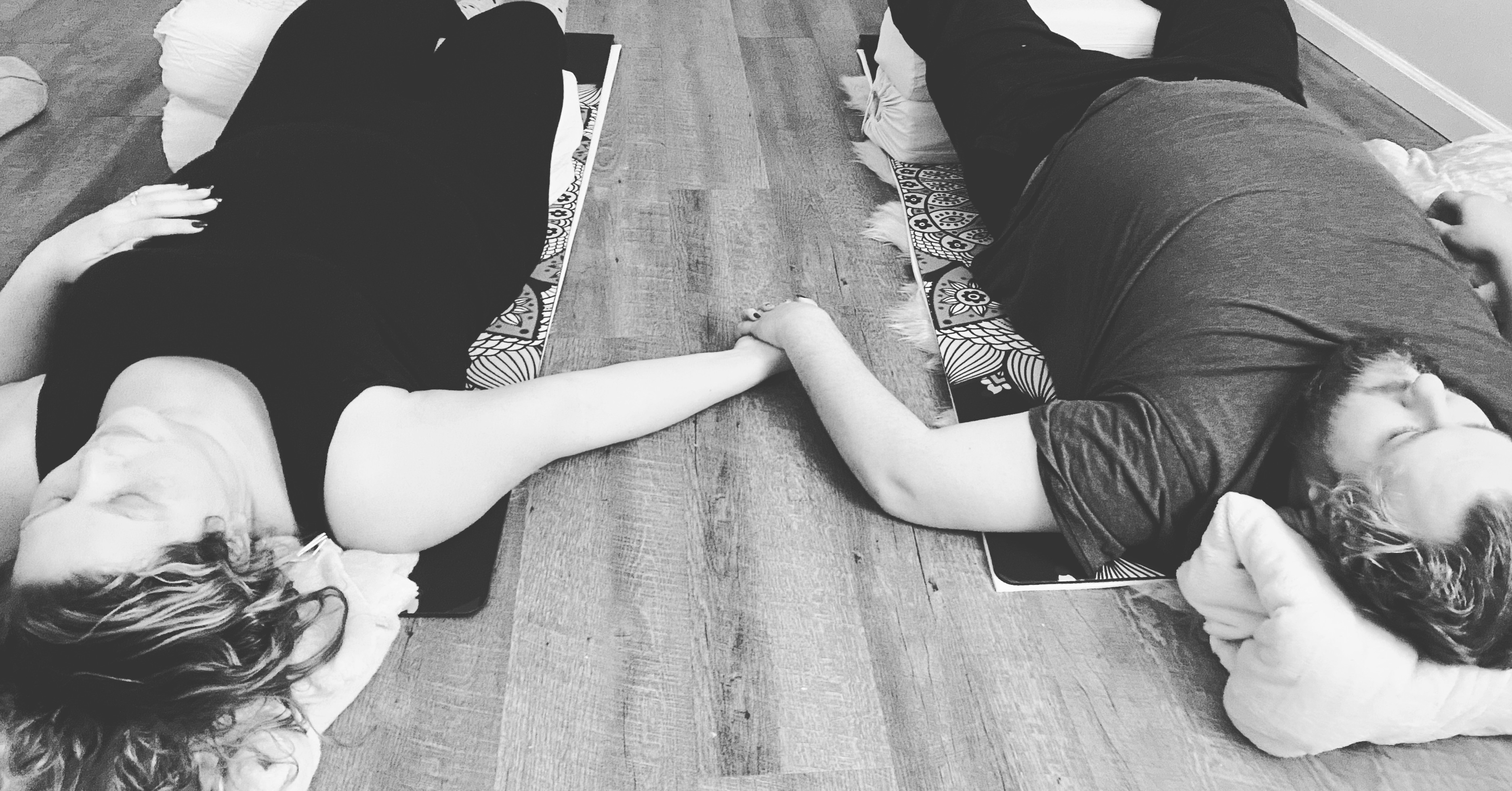 Couple holding hands on a yoga mat